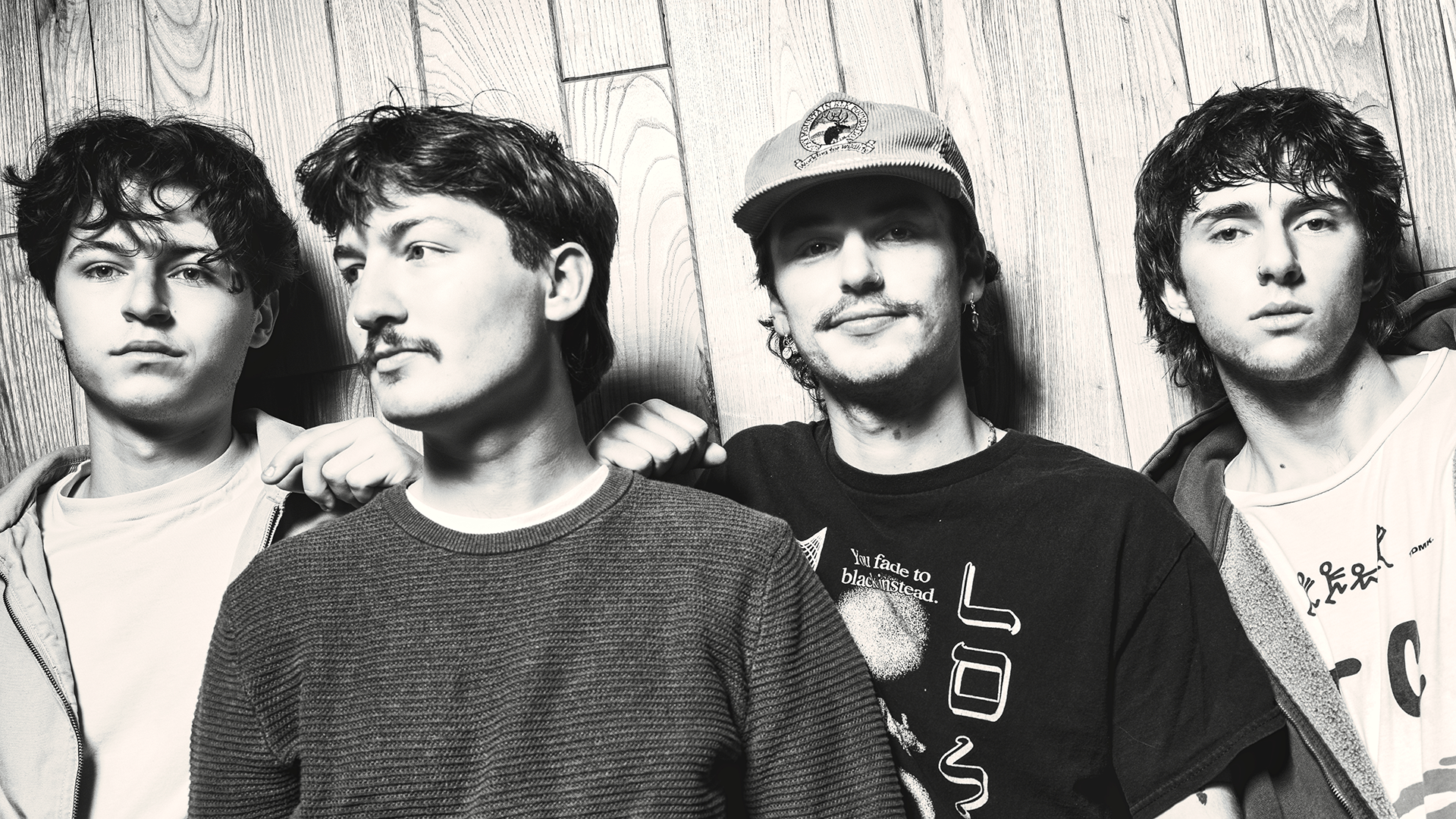 Black and white photo of dadlore posing together against a wooden paneled wall.