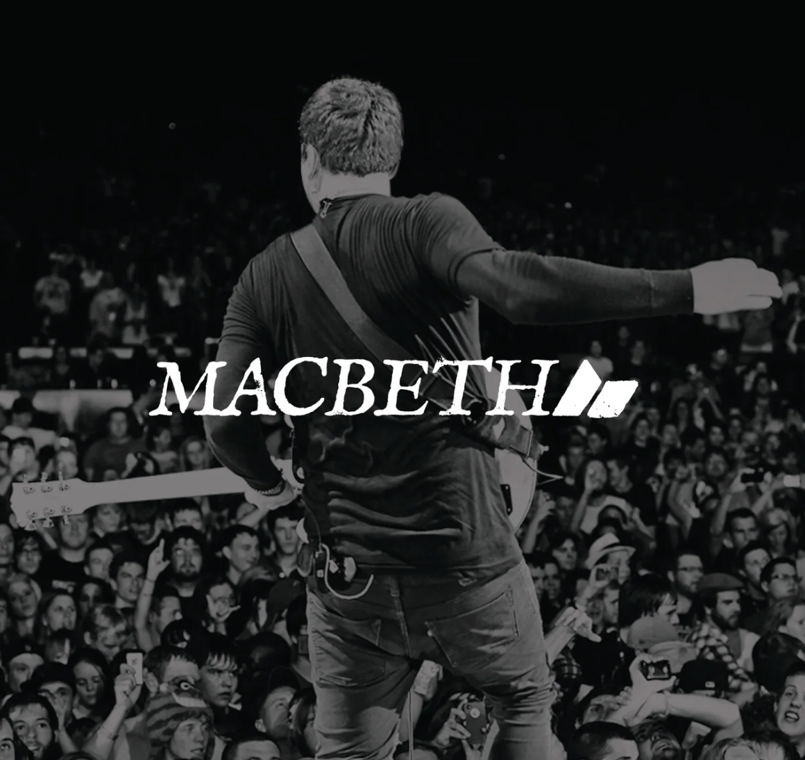 Tom Delonge on stage with 'Macbeth' logo in front of a crowd