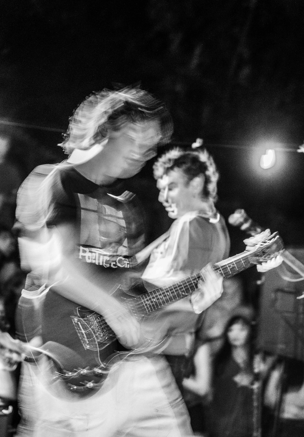 Person playing guitar on stage with a crowd in the background